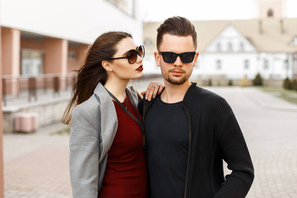 Beautiful young couple in sunglasses and fashionable clothes in the city.