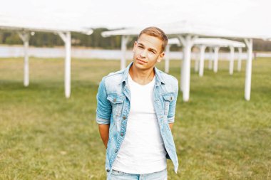 Genç adam bir kot ceket ve Beyaz tişört doğa üzerinde poz