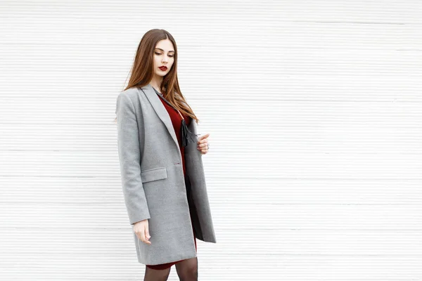 Mulher em casaco de moda cinza perto de parede de madeira branca — Fotografia de Stock