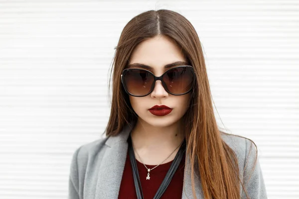 Retrato de una hermosa joven en gafas de sol en la calle cerca de una pared de madera blanca —  Fotos de Stock