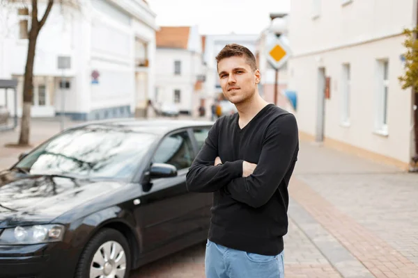 Bonito homem em uma camiseta preta perto de um carro na cidade — Fotografia de Stock