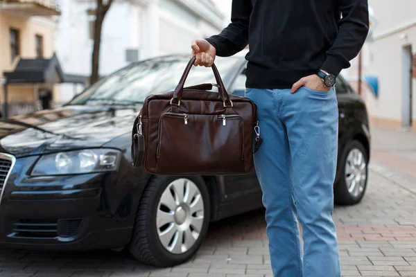 Affärsman man innehar en läderväska nära bilen — Stockfoto