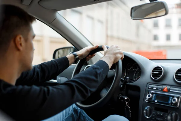 Mladý muž řidič sedí v autě a držení volantu — Stock fotografie