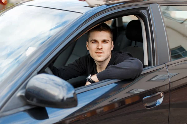 Bonito jovem motorista masculino em um carro preto — Fotografia de Stock