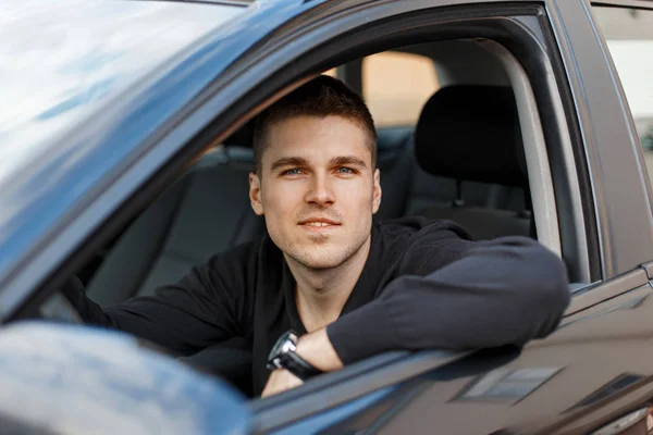 Bonito jovem motorista masculino em um carro preto — Fotografia de Stock