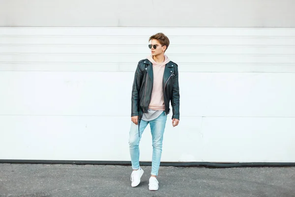 Joven chico guapo en ropa de marca de moda cerca de los caminantes de metal blanco en la calle — Foto de Stock