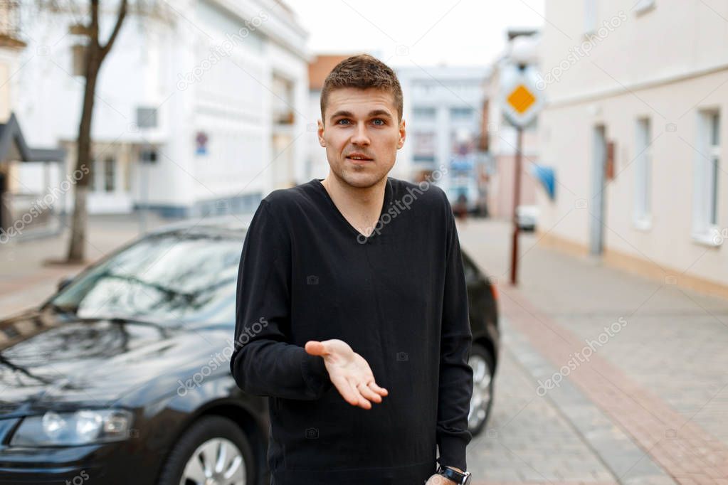 man shows an emotion of indignation near the car on the street