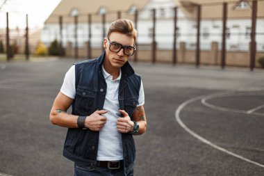 Vintage gözlüklü beyaz bir gömlek ve denim yelek giymiş yakışıklı adam