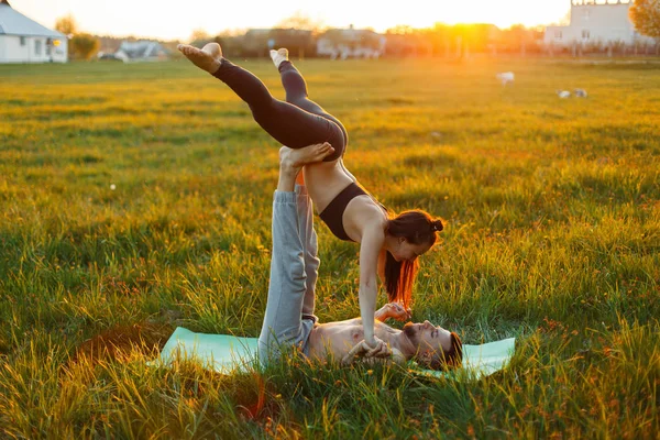 Νεαρό ζευγάρι κάνει γιόγκα στο ηλιοβασίλεμα. Υγιή τρόπο ζωής — Φωτογραφία Αρχείου