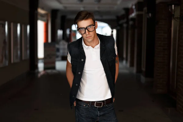 デニムのチョッキと白の t シャツでおしゃれなメガネでハンサムな若い男 — ストック写真