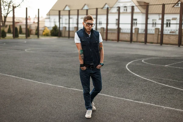 Knappe jonge man met bril in vintage jeans stijl wandelen langs de straat — Stockfoto