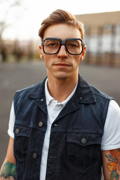 Вінтажний портрет красивого молодого чоловіка з окулярами та джинсовим одягом на вулиці — стокове фото