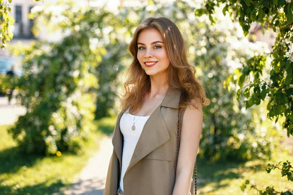 Glückliche schöne Frau in modischen Markenklamotten posiert an einem sonnigen Tag im Park — Stockfoto