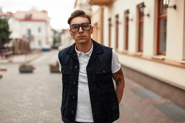 Joven guapo con gafas y ropa vaquera en la ciudad — Foto de Stock