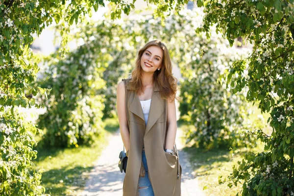 Ευτυχής όμορφη γυναίκα με χαριτωμένο χαμόγελο με μοντέρνα ρούχα στο πάρκο μια ηλιόλουστη ημέρα άνοιξη — Φωτογραφία Αρχείου