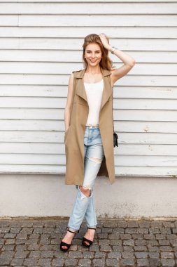 Mutlu genç kadın moda giysiler, kot pantolon ve siyah bir çanta ayakkabılarla bir gülümseme güneşli bir bahar