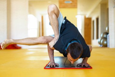 Pratik yoga ya da el ayakta poz yoga mat salonunda genç adam