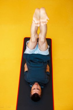 Sarı arka planda, üstten görünüm germe yapan genç erkek