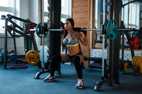 Entrena a una mujer en el gimnasio. Hermosa joven haciendo ejercicio — Foto de Stock