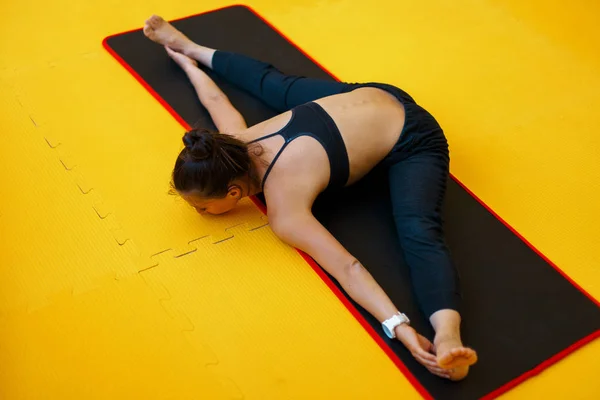 Mulher bonita fazendo ioga e esticando as pernas em um fio em um fundo amarelo — Fotografia de Stock