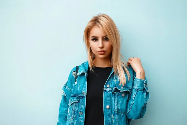 Mooi jong meisje in trendy stijlvolle denim kleding in de buurt van blauwe muur — Stockfoto