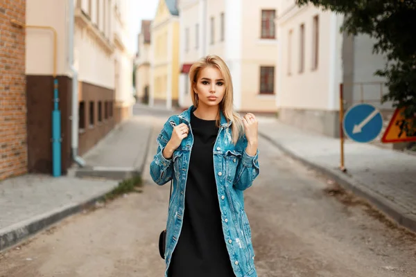 Giovane donna con una borsa in jeans alla moda che cammina per strada — Foto Stock