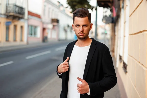 Stilvoller junger Mann in schwarzer Businessjacke posiert auf der Straße — Stockfoto