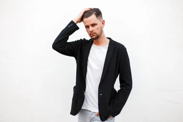 Stylischer junger Mann in Businesskleidung in der Nähe einer weißen Wand — Stockfoto