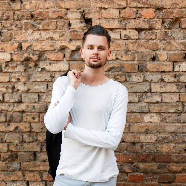 Knappe modieuze man met een kapsel in een wit overhemd in de buurt van een muur — Stockfoto