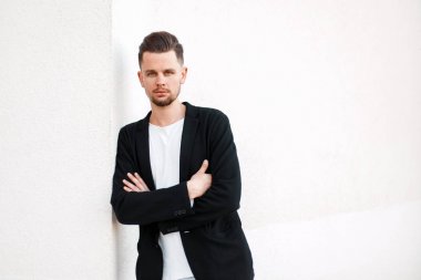 Yakışıklı genç adam beyaz duvarının yakınında şık iş elbiseleri