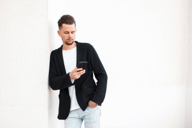 Beyaz duvar yakın cep telefonuyla yakışıklı genç