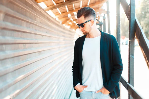 Knappe jongeman in zakelijke kleding in zonnebril in de buurt van een metalen muur op de zonnige dag — Stockfoto