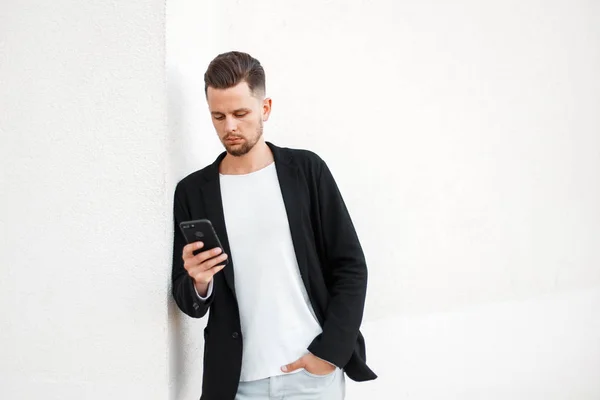 Современный молодой бизнесмен с мобильным телефоном в стильной одежде на белом фоне — стоковое фото