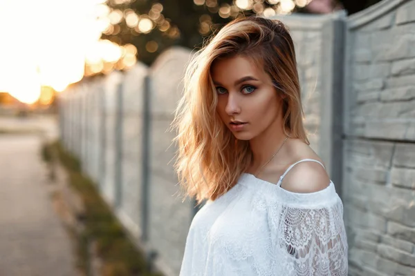 Retrato de uma linda garota loira em uma camiseta de renda branca vintage ao pôr do sol — Fotografia de Stock