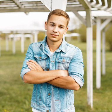 Vintage bir ahşap beach gölgelik yakınındaki bir kot ceketli yakışıklı bir genç adam portresi