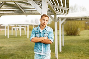 Yakışıklı genç bir ahşap beach gölgelik yakınındaki bir kot ceketli
