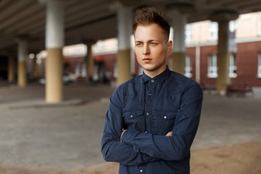 Genç yakışıklı bir köprü altında sokakta mavi gömlekli olan