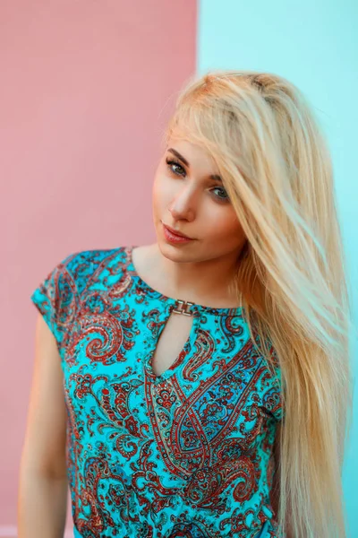 Yaz parlak mavi ve pembe duvarının yakınında desenleri ile mavi elbiseli güzel bir genç sarışın kadın portresi