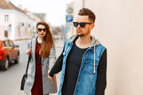 Красивая стильная молодая пара в солнечных очках в модной одежде гуляет по городу. Любовники . — стоковое фото