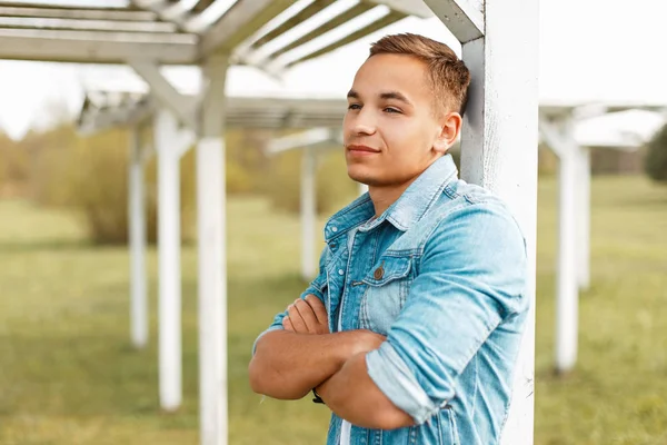 Yakışıklı genç adam ahşap beach gölgelik yakınındaki şık denim ceket.
