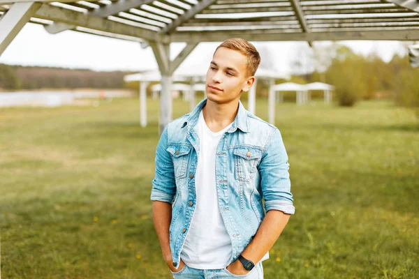 Doğal bir kot ceket ve beyaz bir gömlek Beyaz ahşap kubbe yakınındaki genç bir adam portresi