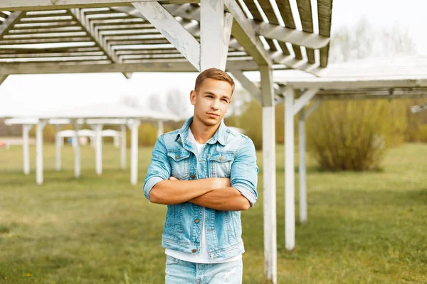 Yakışıklı genç bir ahşap beach gölgelik yakınındaki bir kot ceketli