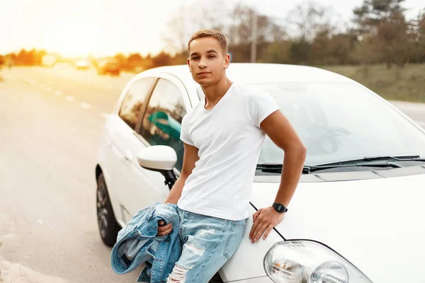 Bonito jovem está viajando de carro ao pôr do sol — Fotografia de Stock