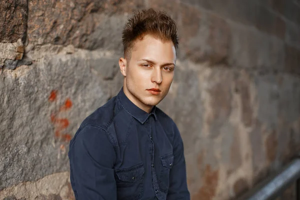 Mavi gömlekli bir duvara yakın genç bir adam portresi