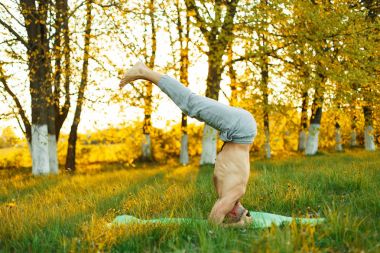 pratik Yoga parkta günbatımı, sağlıklı lifestyl, çim adam