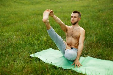 Yoga pratik Park sırasında tekne poz yapan genç erkek