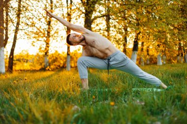 Gün batımında pratik Yoga parkta genç adam. Sağlıklı yaşam tarzı