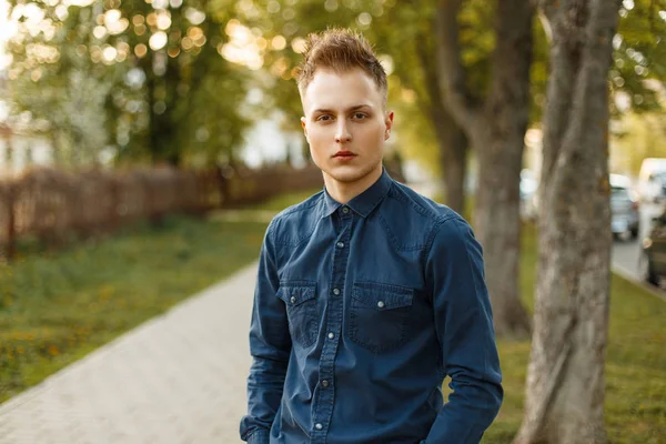 Hombre joven con una camisa azul en el parque en un día soleado de primavera —  Fotos de Stock