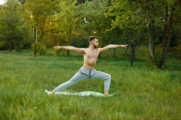 Mann praktiziert Yoga im Garten auf dem Rasen — Stockfoto