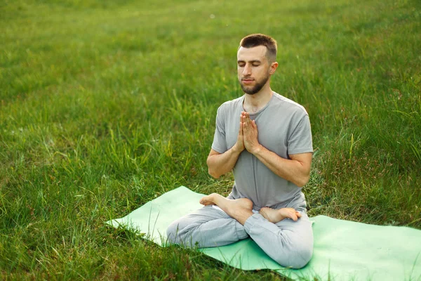 Man doing yoga in the park on nature. Meditation — Stock Photo, Image